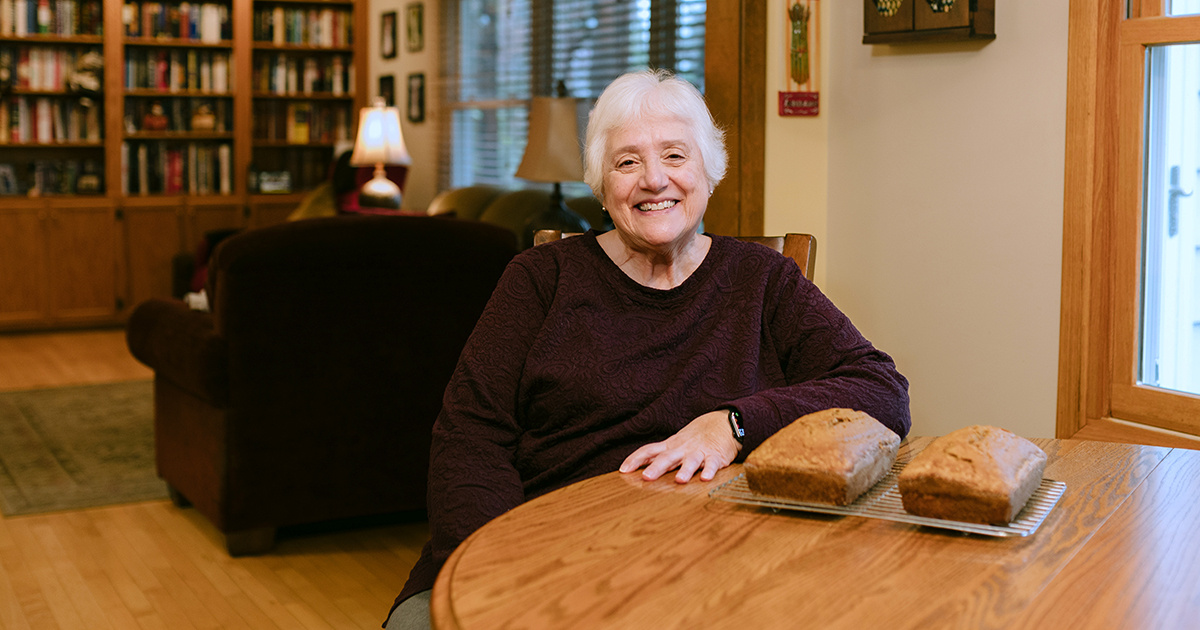 Georgia sitting at her kitchen table with two freshly baked loaves of bread.