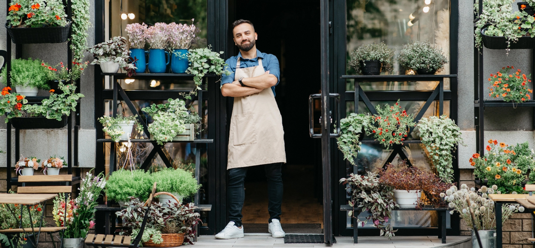 Business owner of plant store standing confidently in store doorway.