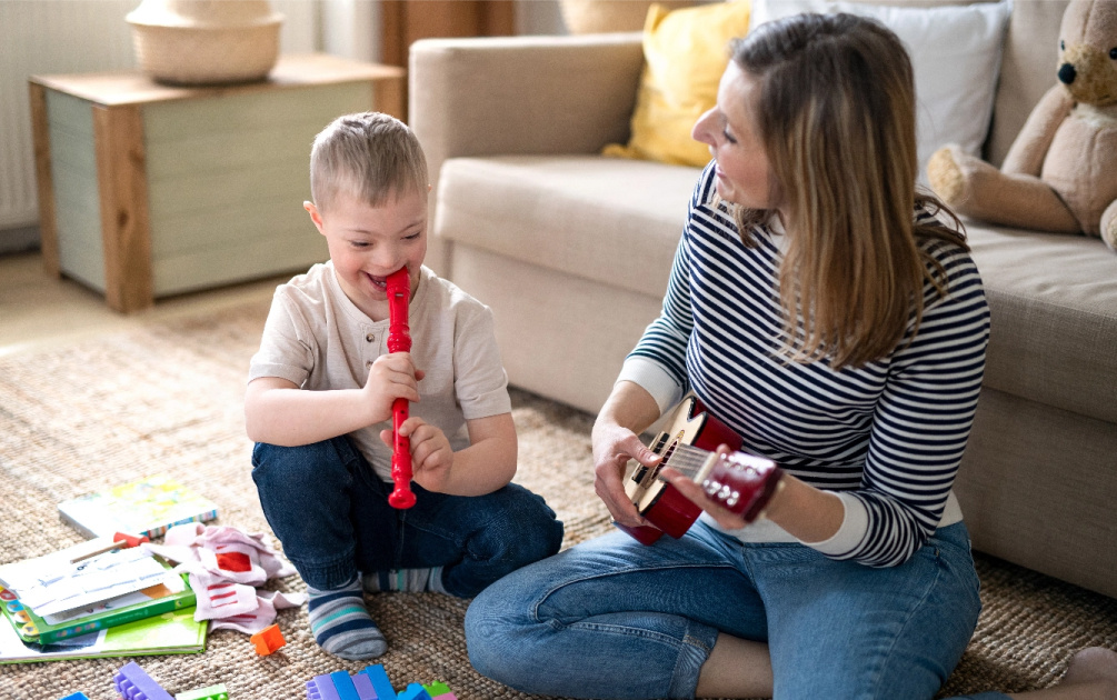 A young boy plays the recorder while a woman plays a ukulele
